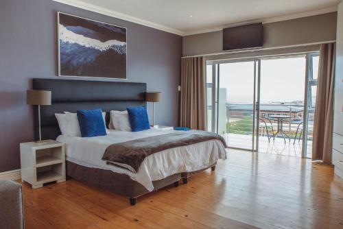 a bedroom with a bed with blue pillows and a balcony at Harbour Lights Luxury Loft in Port Elizabeth