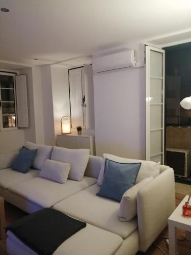 ein Wohnzimmer mit einem weißen Sofa und blauen Kissen in der Unterkunft Casa do Coronel in Alcochete