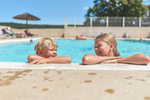 une femme et un enfant dormant dans une piscine dans l'établissement Château De Chaussy, à Ruoms