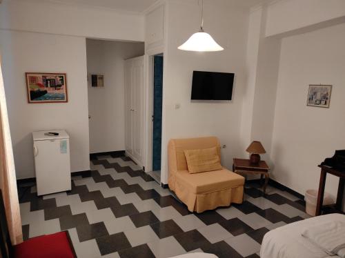 a living room with a chair and a television at Ariadni Rooms & Apartments in Ermoupoli