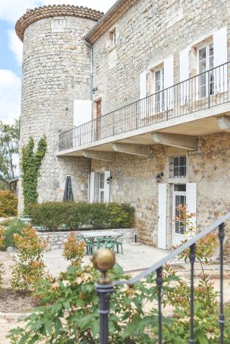- un bâtiment en pierre avec une table et un balcon dans l'établissement Château De Chaussy, à Ruoms