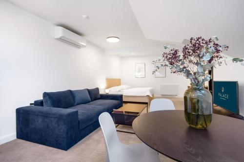 a living room with a blue couch and a table with flowers at Palace Apartments in Bratislava