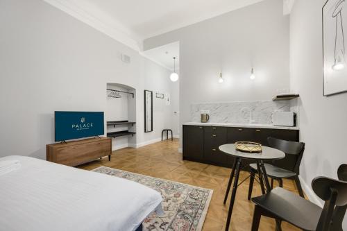a room with a bed and a table and a kitchen at Palace Apartments in Bratislava