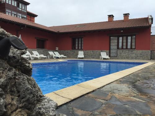 a swimming pool with chairs and a red house at Casa Josefita in Villamayor