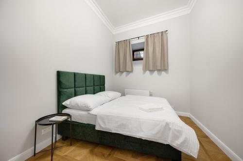 a small bedroom with a bed with a green headboard at Palace Apartments in Bratislava