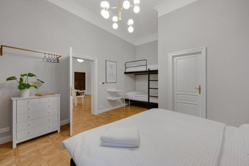 a white bedroom with a bed and a desk at Palace Apartments in Bratislava