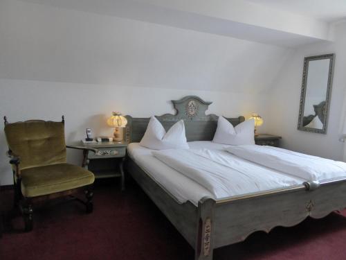 a bedroom with a large bed and a chair at Hotel Haus Appelberg in Dinkelsbühl