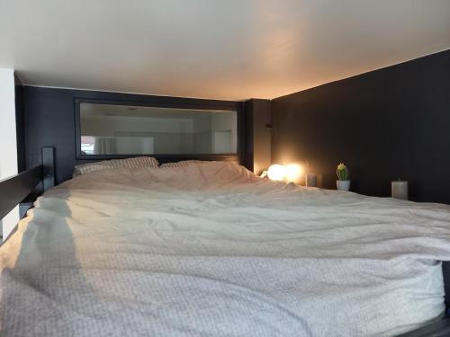 une chambre avec un grand lit blanc avec une grande fenêtre dans l'établissement Studio avec terrasse en résidence calme à Dijon., à Dijon