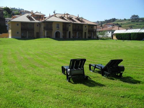 two chairs sitting in the grass in front of a house at Hotel Apartamentos La Hortona in Soto de Luiña