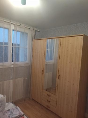 a wooden cabinet in a room with two windows at chambre privée chez l'habitant et partage des partie communes in Chail