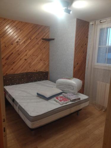 a small bed in a room with a wooden wall at chambre privée chez l'habitant et partage des partie communes in Chail