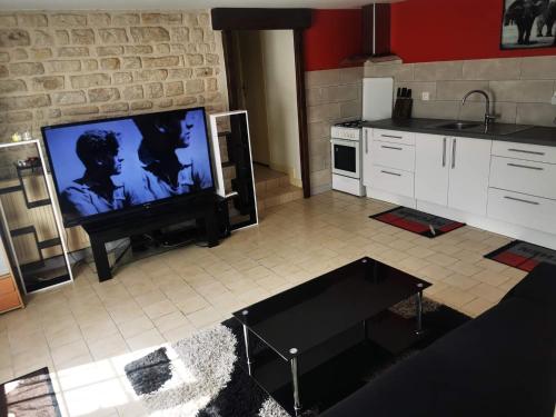 a living room with a flat screen tv and a kitchen at chambre privée chez l'habitant et partage des partie communes in Chail