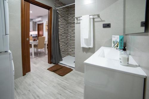 y baño blanco con lavabo y ducha. en Apartamentos Maquinista en Puente-Genil