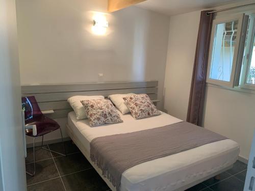 ein Schlafzimmer mit einem Bett mit zwei Kissen und einem Fenster in der Unterkunft L'Aparte - T3 Les Oliviers in Pignans
