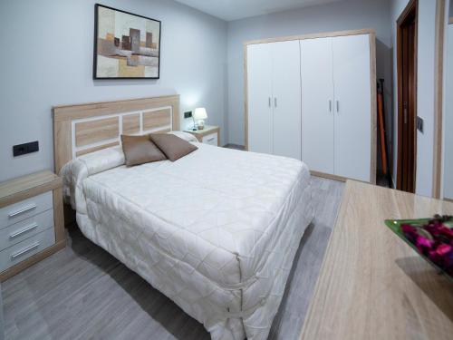 1 dormitorio con 1 cama blanca y armario blanco en Apartamentos Maquinista en Puente-Genil