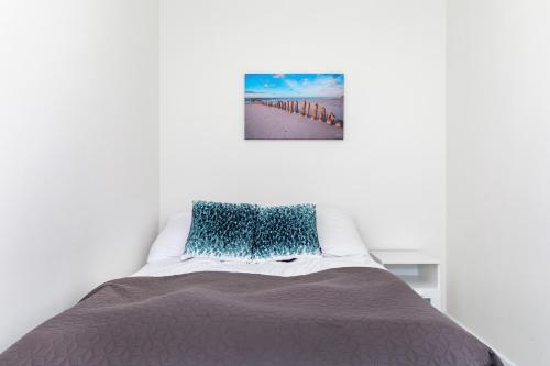 a bedroom with a bed with a picture on the wall at Jantar Apartamenty - 5 Mórz Sianożęty in Sianozety