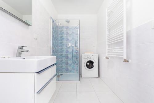 a white bathroom with a shower and a washing machine at Jantar Apartamenty - 5 Mórz Sianożęty in Sianozety