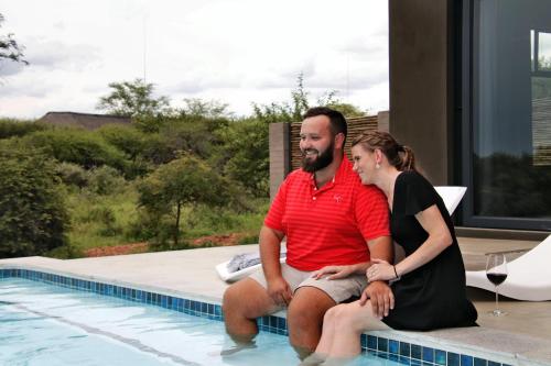a man and a woman sitting next to a swimming pool at Umkhaya in Marloth Park