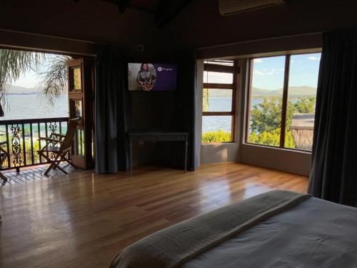 a bedroom with large windows and a view of the water at Marina Views Guesthouse in Hartbeespoort