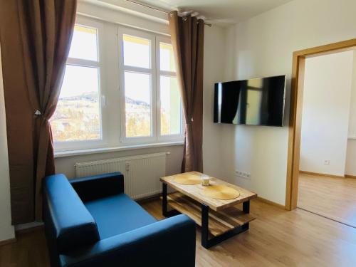 ein Wohnzimmer mit einem blauen Sofa und einem Tisch in der Unterkunft Apartmán Na Křížku 2+kk, Skiareál Klínovec 10minut in Vejprty