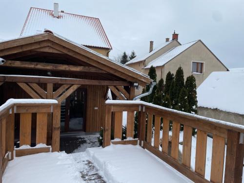 a wooden deck with snow on the ground at Öskarszt apartman in Úrkút