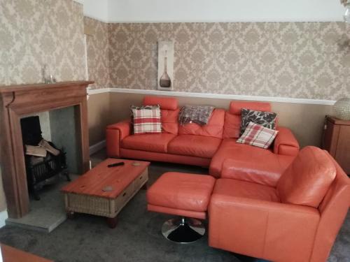 a living room with a red couch and a fireplace at Carvetii - Halite House - 3 bed House sleeps up to 5 people in Tillicoultry