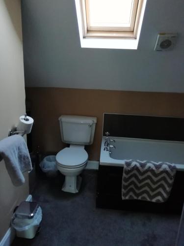 a bathroom with a toilet and a tub and a window at Carvetii - Halite House - 3 bed House sleeps up to 5 people in Tillicoultry