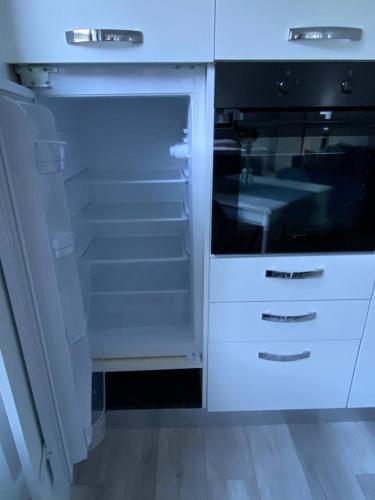a white kitchen with an open refrigerator at Garda View Apartment in Tenno
