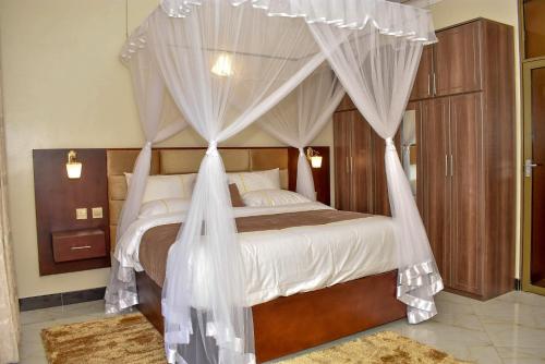 a bedroom with a canopy bed with white drapes at Jengel Studio Furnished Apartments in Entebbe