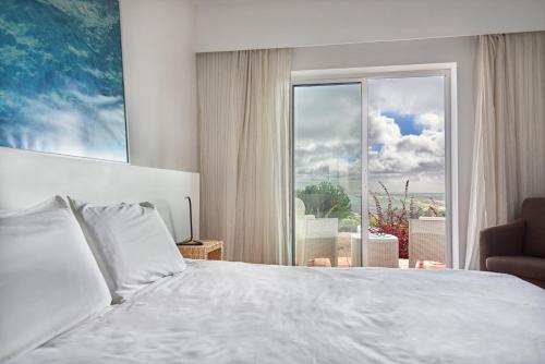 a bedroom with a bed and a large window at Alto da Lua in Aljezur