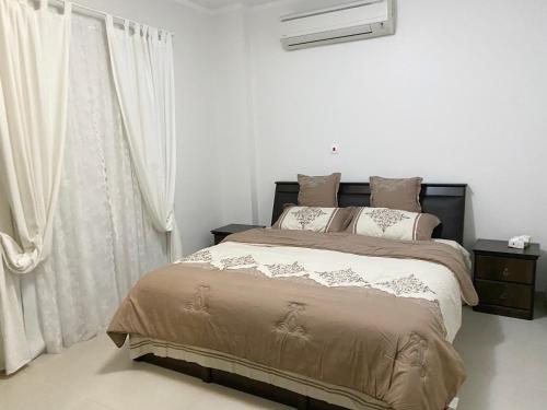 Un dormitorio con una cama grande y una ventana en شقة الواحة روز - Alwaha Rose, en King Abdullah Economic City