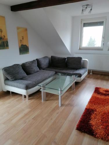 uma sala de estar com um sofá e uma mesa de vidro em Ferienwohnung Yara Rödental em Rödental