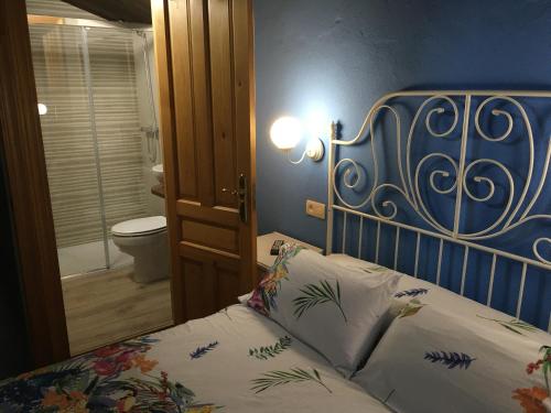 a bedroom with a bed with a blue headboard and a toilet at La Terraza de Onís in Bobia de Arriba