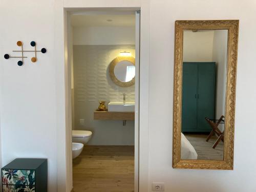 baño con espejo y lavabo en Combo Rooms-Suites, en Garna dʼAlpago