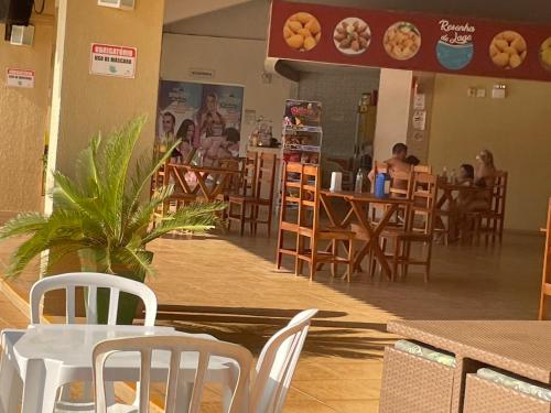 a restaurant with white tables and chairs and people at tables at Apartamento em Caldas Novas in Caldas Novas
