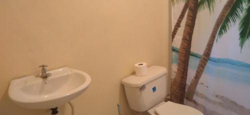 a bathroom with a toilet and a sink and palm trees at Lovely 1-Bed Cottage in St catherine Jamaica in Ewarton