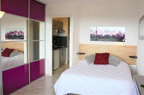 - une chambre avec un lit blanc et des placards violets dans l'établissement Cap d'Agde Naturist Héliopolis O 33, au Cap d'Agde