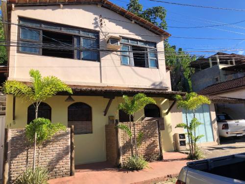 a white house with trees in front of it at Casa no centro da cidade com garagem. in Itacaré