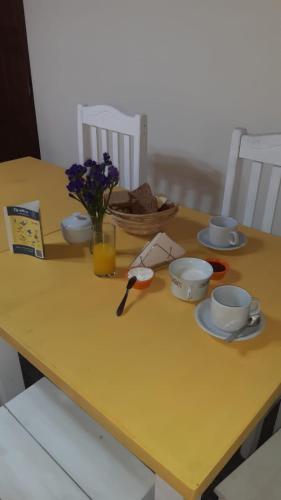Ein gelber Tisch mit Tellern und Tassen und einer Vase mit Blumen in der Unterkunft Posada Mis Padres in Godoy Cruz