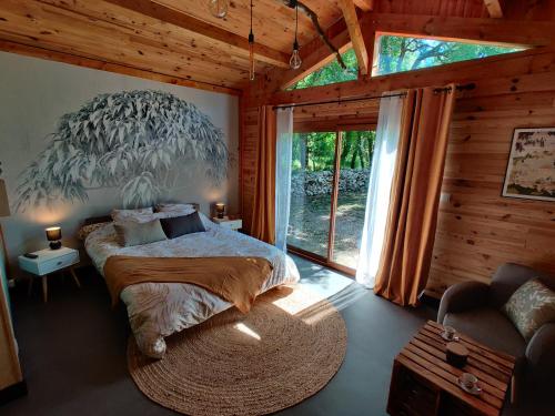 a bedroom with a large bed and a large window at Chalet, bain nordique (spa) dans le triangle noir in Quissac