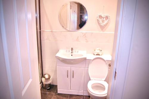 W łazience znajduje się toaleta, umywalka i lustro. w obiekcie Dawn Break Guest House w mieście Largs