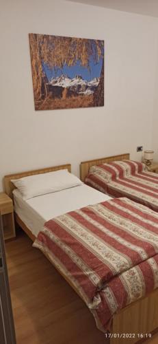 ein Schlafzimmer mit 2 Betten und einem Bild an der Wand in der Unterkunft Casa Brugnara in Pozza di Fassa