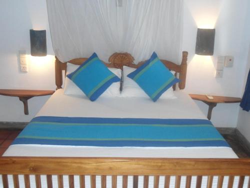 a bedroom with a bed with blue and white pillows at Little Paradise Tourist Guest House and Holiday Home in Anuradhapura