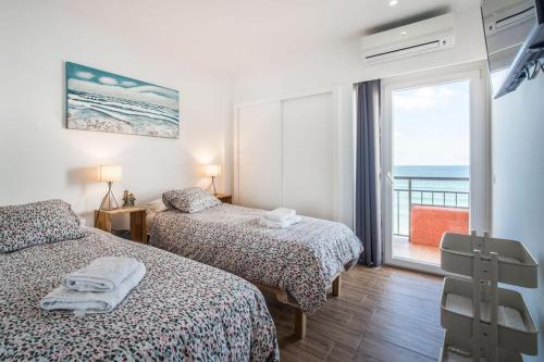 two beds in a room with a view of the ocean at Beachfront Fuengirola Dreamin in Fuengirola