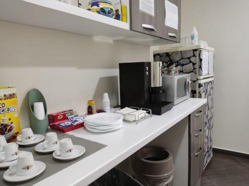 a kitchen counter with cups and plates and a microwave at Civico 83 in Reggio Calabria