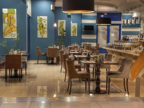 un restaurante con mesas, sillas y paredes azules en Trokadero Boutique Hotel, en Itea