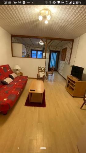 un salon avec un canapé rouge et une table dans l'établissement Les Geraniums, à Colligny
