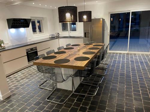 a large kitchen with a long wooden table and chairs at Gîte le belloy'Zo in Belloy sur Somme