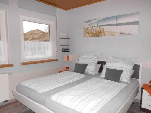 a bedroom with a bed with white sheets and a window at Ferienwohnung Schöne Aussicht in Diemelsee