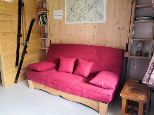 um sofá vermelho com almofadas cor-de-rosa num quarto em Résidence "Rado" em Samoëns